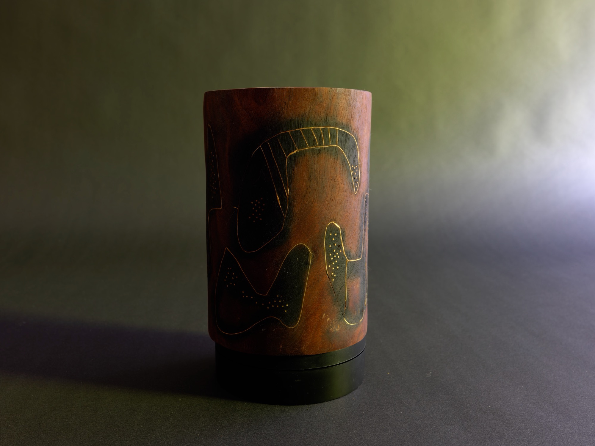 Dream — horizontal view of the inscribed cylinder against the grey-green studio backdrop.