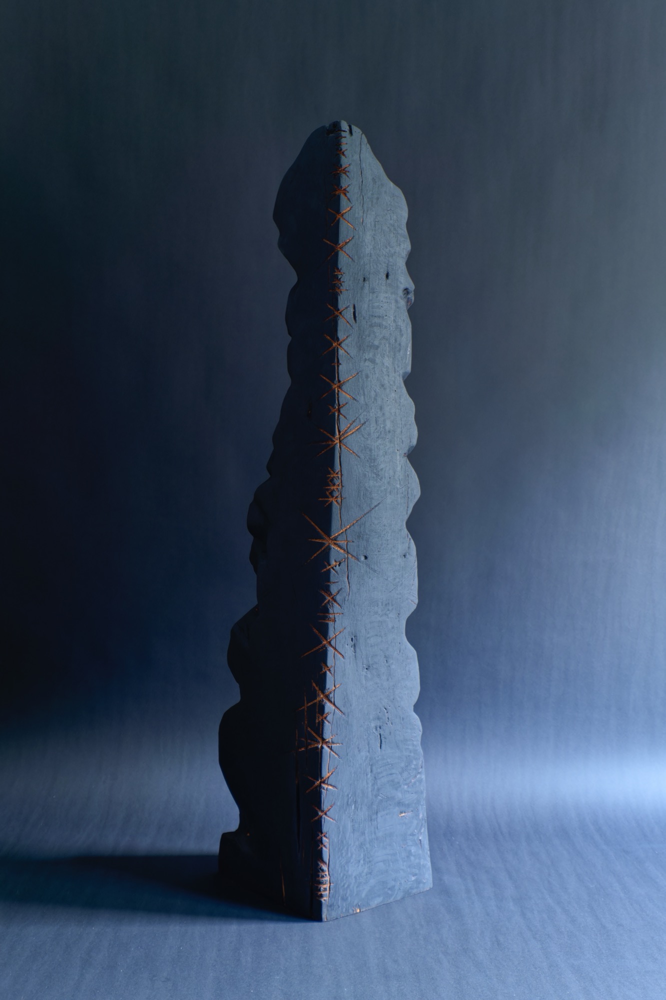 Healing 3 — a tall charred blue-black obelisk stitched with copper-orange crosses, against a deep blue backdrop.